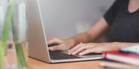 Close-up of female's hands typing on laptop with blurred backgroundの写真素材