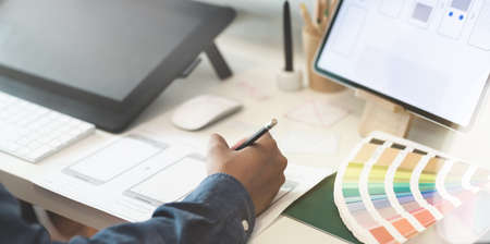 Close-up view of UI designer's hand drawing smart phone template with blurred backgroundの写真素材