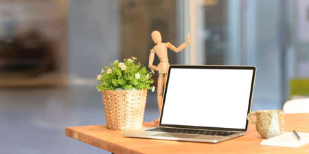 Open blank screen laptop computer on wooden table in comfortable office workspaceの写真素材