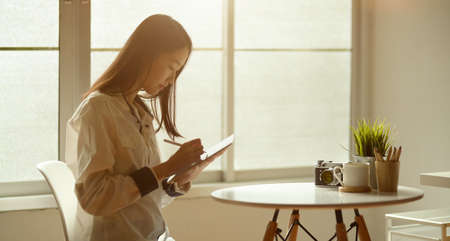 Side view of beautiful asian girl using laptop in her modern work placeの写真素材