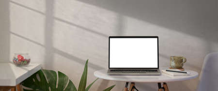Open laptop with blank screen on white table in loft workspaceの写真素材