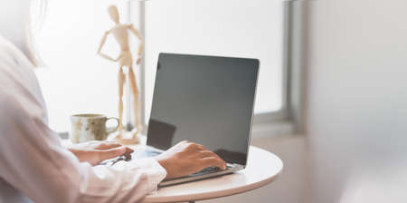 Young female freelancer typing on laptop computer in her modern workspaceの写真素材