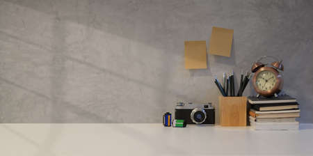 Simple photographer workplace with vintage camera and office supplies with grey wall backgroundの写真素材