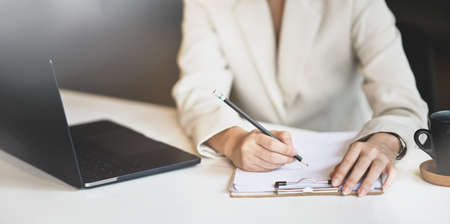 Young professional businesswoman writing her strategy on papers in trendy office roomの写真素材