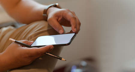 Businessman working on his project while using blank screen smartphoneの写真素材