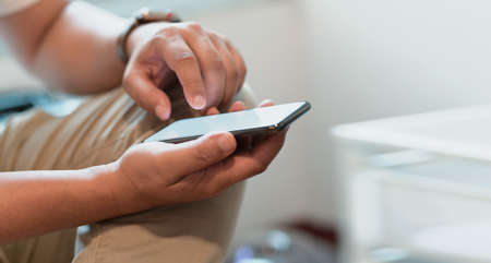 Close-up view of male freelancer hand's touching blank screen smartphone in modern officeの写真素材