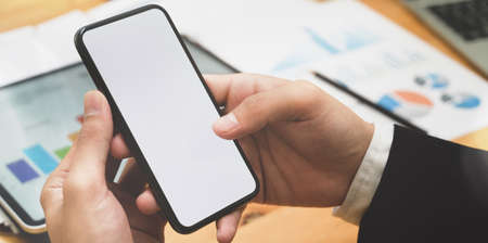 Close-up of young businessman's hand holding blank screen smartphone in meeting roomの写真素材