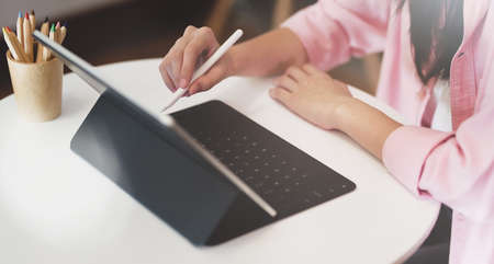 Young female graphic designer working on her project with tablet on white wooden tableの写真素材