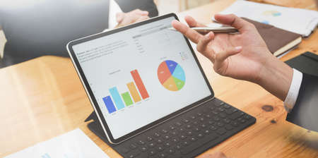 Close-up of successful business team planing the strategy with graphs and charts with tablet on modern office roomの写真素材