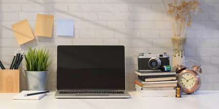 Open laptop with office supplies and decorations in minimal photographer's work stationの写真素材