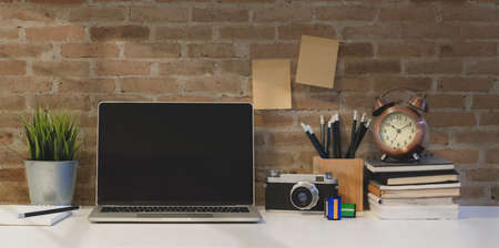Vintage photographer's workplace with open laptop, vintage camera and brick wall backgroundの写真素材