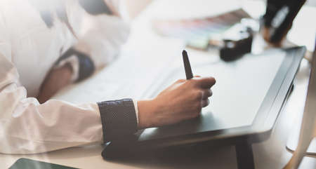 Close-up view of young female graphic designer sketching on tablet in light backgroundの写真素材
