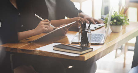 Close-up view of business team writing their ideas in tablet in stylish workplaceの写真素材