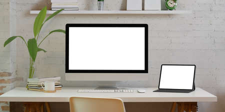 Comfortable home office with blank screen desktop computer and laptop with minimal workplace styleの写真素材