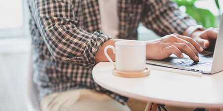 Cropped view of professional male freelancer working on his idea on laptop in comfortable workplaceの写真素材