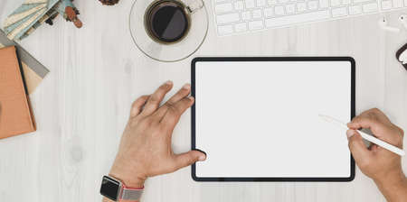 Overhead shot of man working his project with blank screen tablet on white plywood deskの写真素材