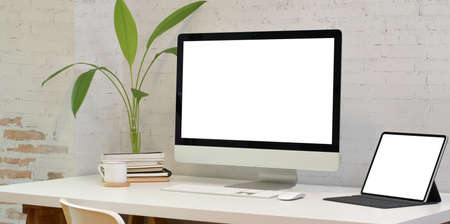 Comfortable office room with blank screen laptop computer and tabletの写真素材