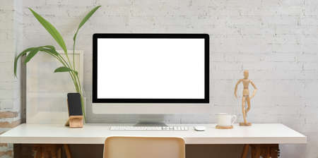 Contemporary workplace with blank screen desktop computer and office suppliesの写真素材