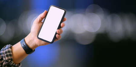 Close-up view of man's left hand holding blank screen smartphone during the night timeの写真素材
