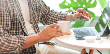 Young male freelancer working in comfortable working space while drinking a cup of coffeeの写真素材