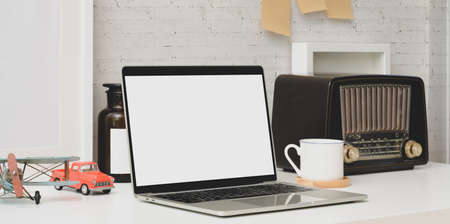 Blank screen laptop computer with vintage retro radio and office supplies in comfortable officeの写真素材
