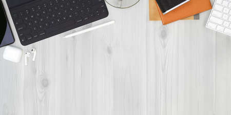 Top view of hipster freelancer workplace with office supplies on white plywood desk backgroundの写真素材