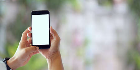 Close-up view of man holding blank screen smartphone with blurred backgroundの写真素材