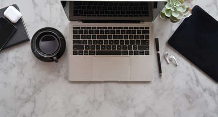 Open laptop with office supplies and decorations on marble desk backgroundの写真素材