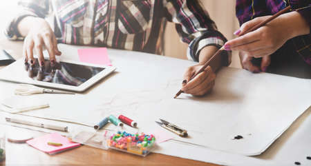 Successful young female designer explaining her idea about the next project to her co-worker in creative studioの写真素材