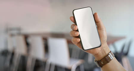 Close-up of man's right hand holding blank screen smartphone with blurred backgroundの写真素材