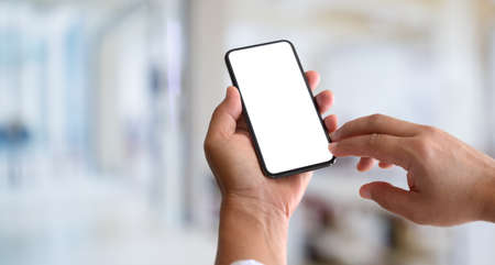 Cropped view of man's hands holding blank screen smartphone with blurred backgroundの写真素材