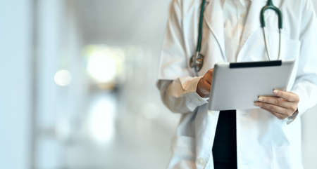Close-up of young professional doctor summarising the patient chart with tablet in hospitalの写真素材