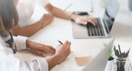 Close-up view of businesswoman partner working on their concepts together in modern officeの写真素材