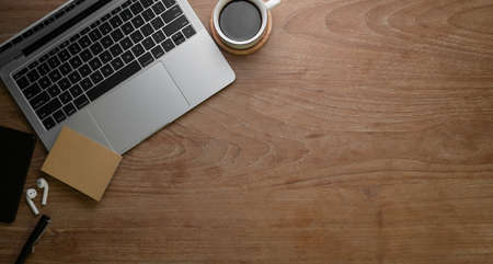 Vintage workplace with office supplies and a cup of black coffee on rustic wooden tableの写真素材