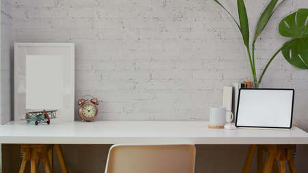 Comfortable home office with copy space, mock up frame and blank screen tablet on white wall backgroundの写真素材