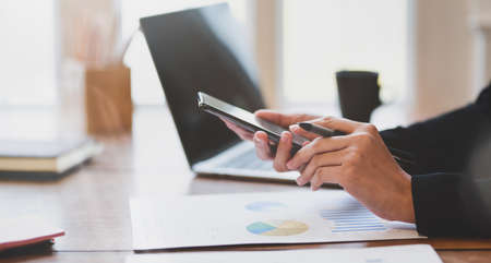 Close-up view of businesswoman's hands holding smartphone in the officeの写真素材