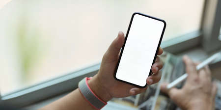 Close-up view of young man surfing the Internet with blank screen smartphoneの写真素材