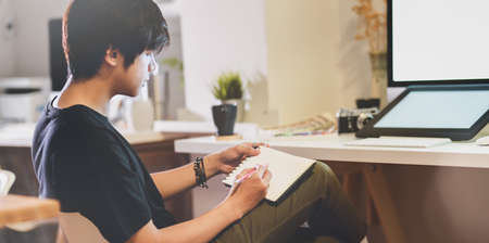 Close-up view of motivated photographer writing his ideas in his workplaceの写真素材