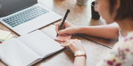 Close-up of businesswoman writing her idea for the upcoming projectの写真素材