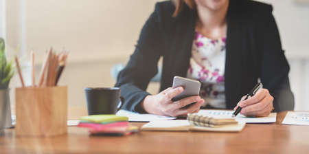Professional businesswoman working on her strategy while using smartphone in workplace