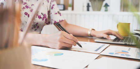 Close-up view of businesswoman working on her upcoming project in modern officeの写真素材