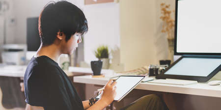 Close-up view of young photographer editing his picture on tabletの写真素材