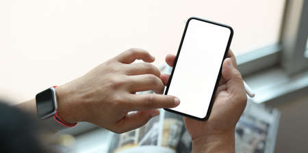 Cropped view of man using his blank screen smartphone during the relax time