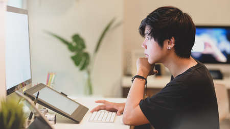 Young professional photographer editing his photo in comfortable officeの写真素材