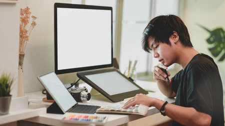 Young professional male photographer retouching his photos with digital tablet in comfortable workplaceの写真素材