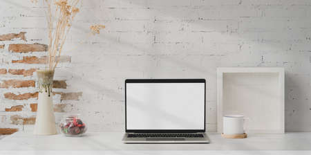 Minimal workplace with open blank screen laptop with mock up frame and office supplies