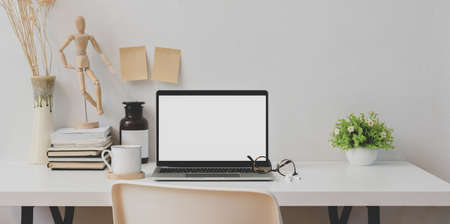 Trendy workplace with open blank screen laptop and office suppliesの写真素材