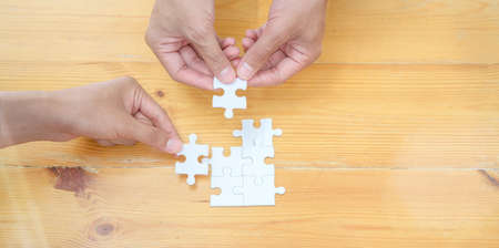 Top view of hands of diverse people assembling jigsaw puzzle together represents teamwork of the groupの写真素材