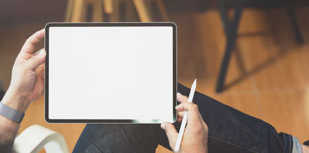 Young male freelancer working on his project with blank screen tablet in minimal home officeの写真素材