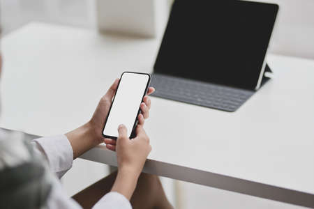 Cropped view of businesswoman holding blank screen smartphone in modern officeの写真素材